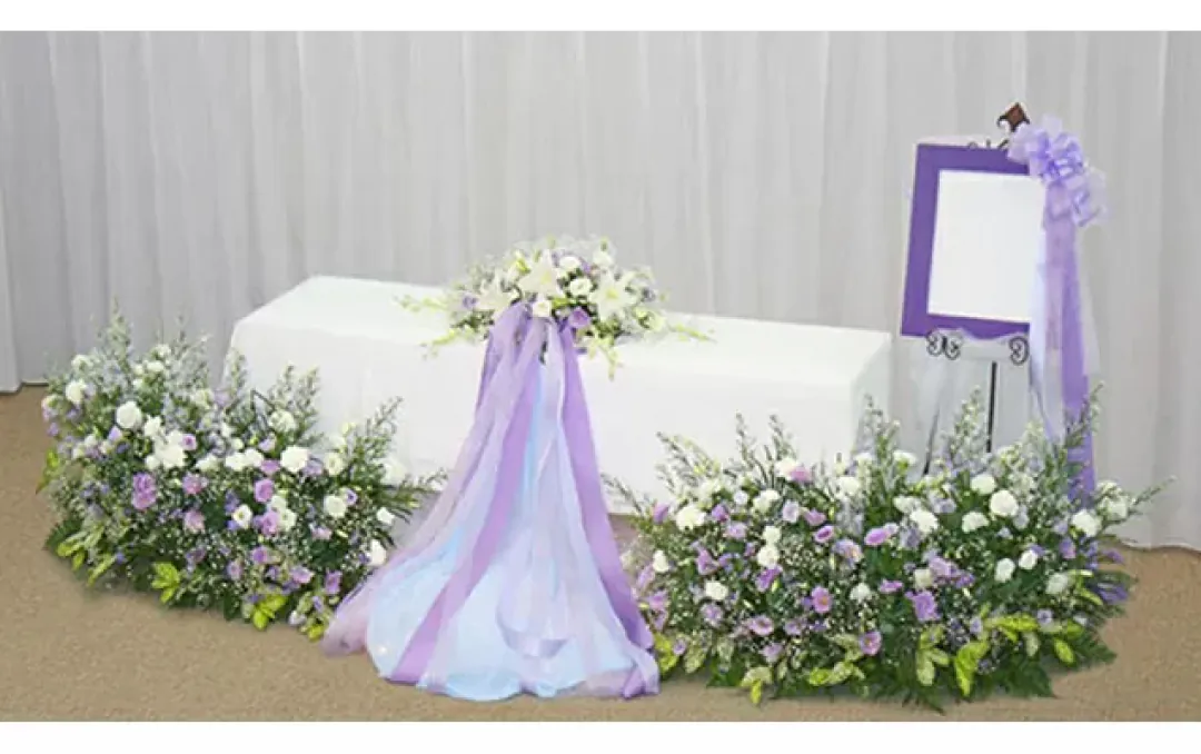 紫と白のリボンで飾られた優雅な花祭壇